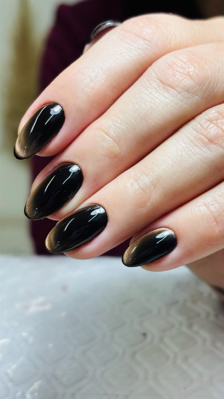 Unhas com esmaltação em gel preto com efeito olho de gato dourado