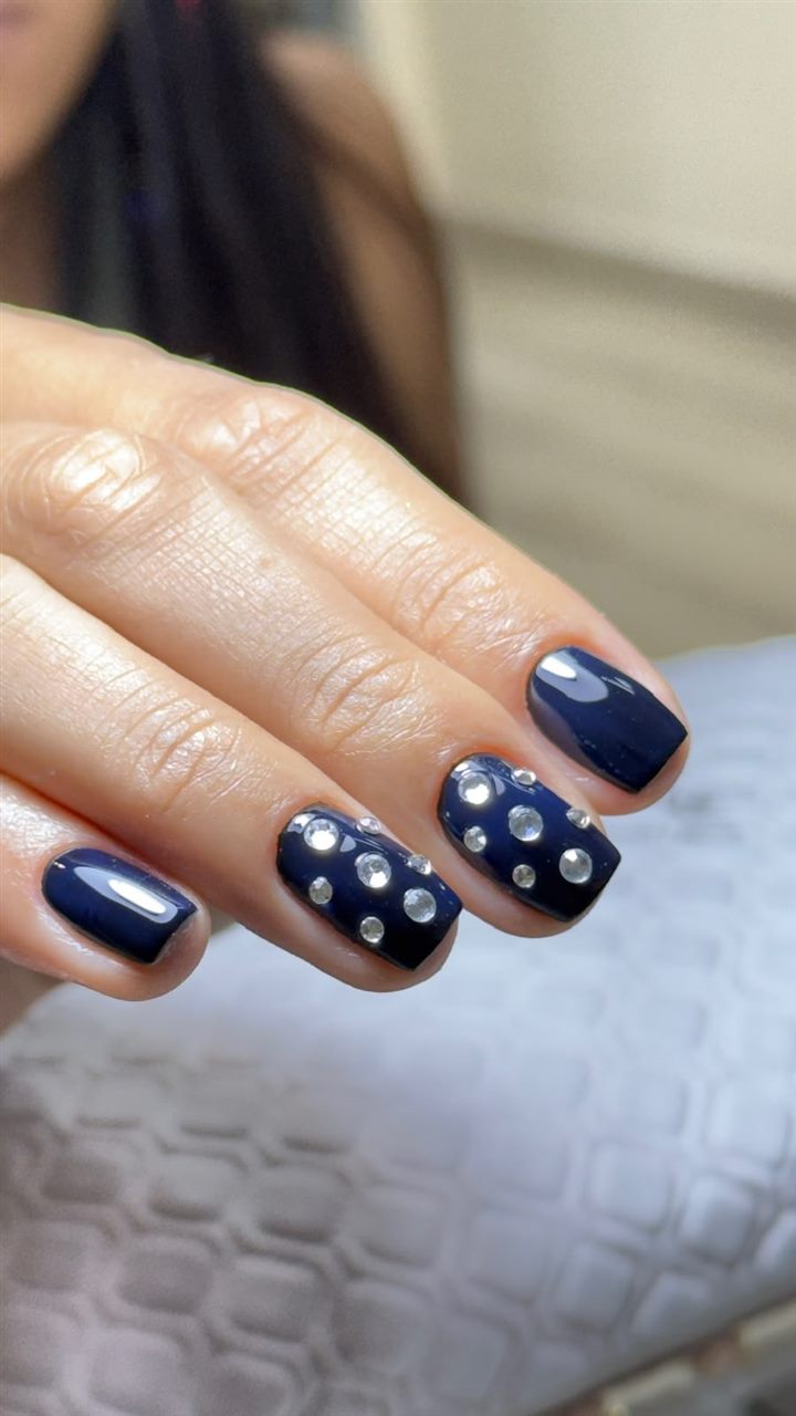 Unhas com esmaltação em gel azul marinho e pedras de strass